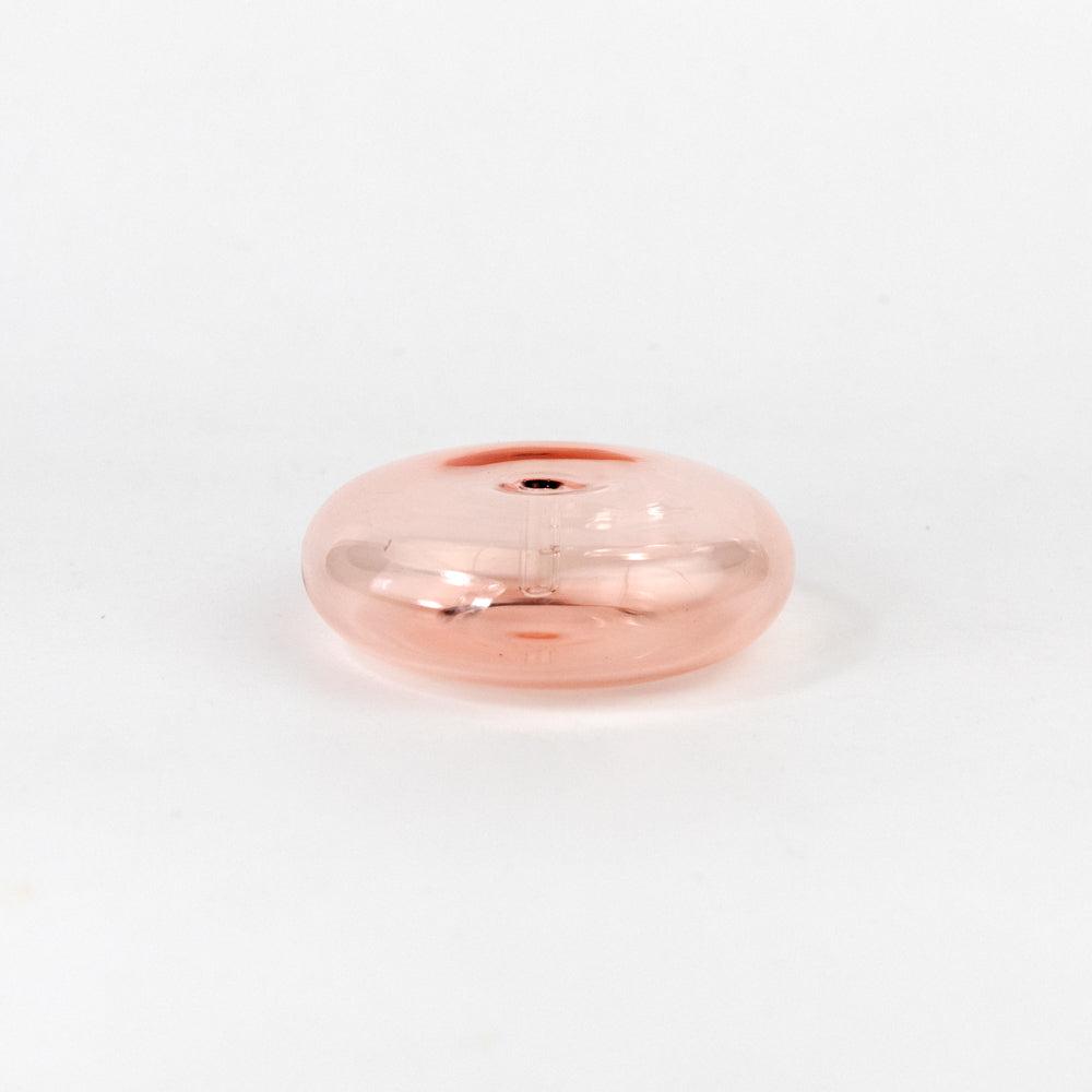 Incense stick in a coral colored glass holder on a white background