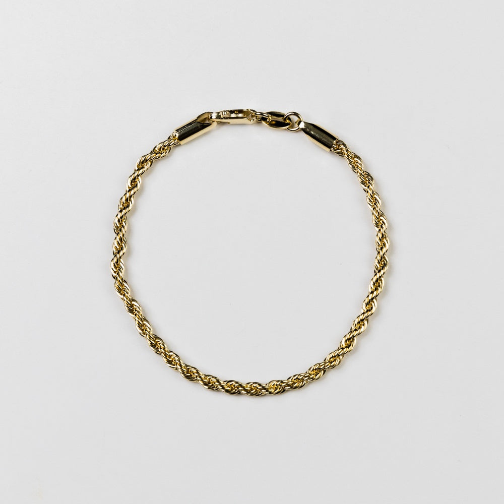 Gold chain bracelet on a light gray background