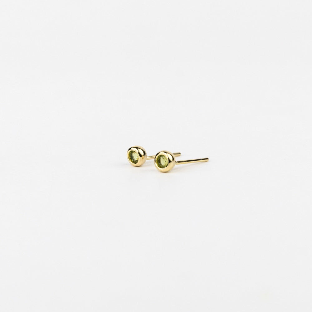 Pair of gold stud earrings with green gemstones on a white background