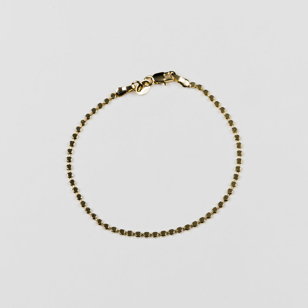 Gold bracelet on a light gray background