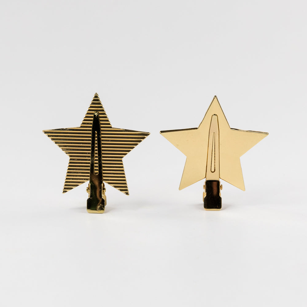 Two star-shaped gold clips on a white background