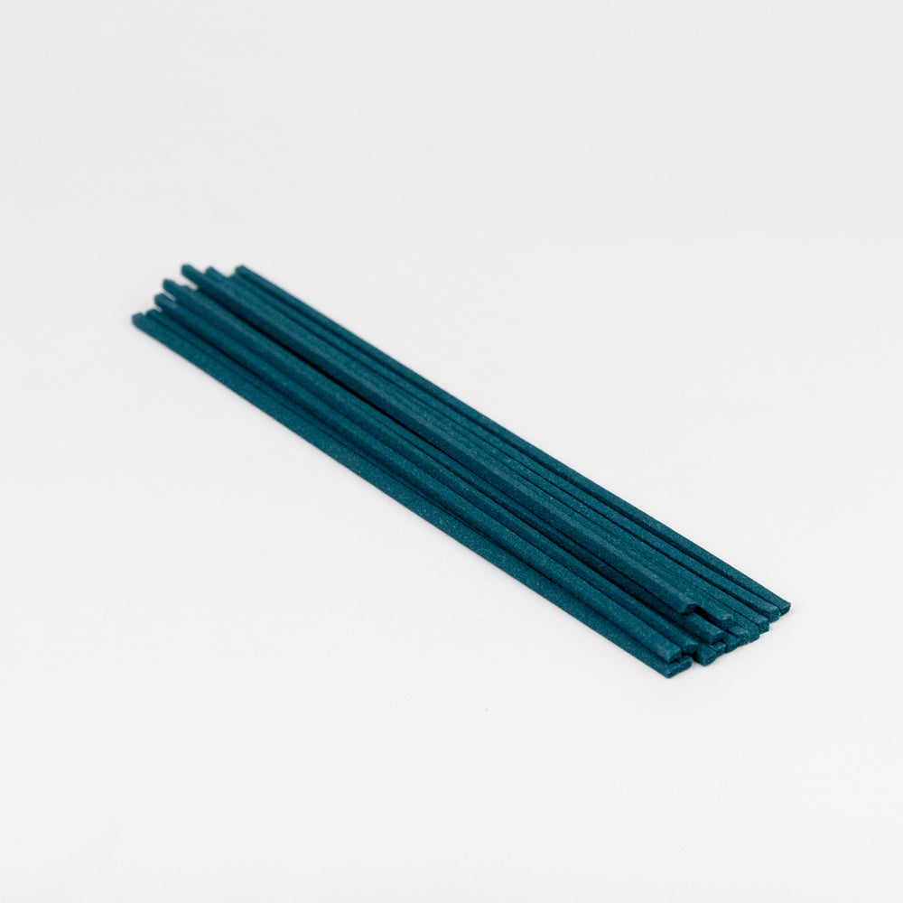 Teal incense sticks on a white background